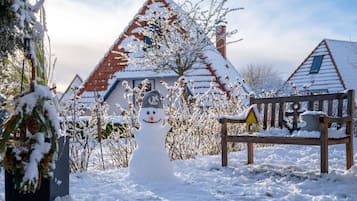 Ein Schneemann in verschneiter Winterlandschaft, im Hintergrund Häuser.