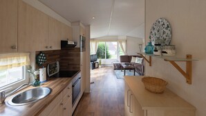 Eine moderne Küche mit Holzausstattung, einem Edelstahl-Spülbecken und einem Essbereich mit einer Couch und einem Tisch.