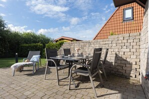 Eine Außenpatio mit Tisch und Stühlen, einer Ziegelwand und einem Ziegeldach.
