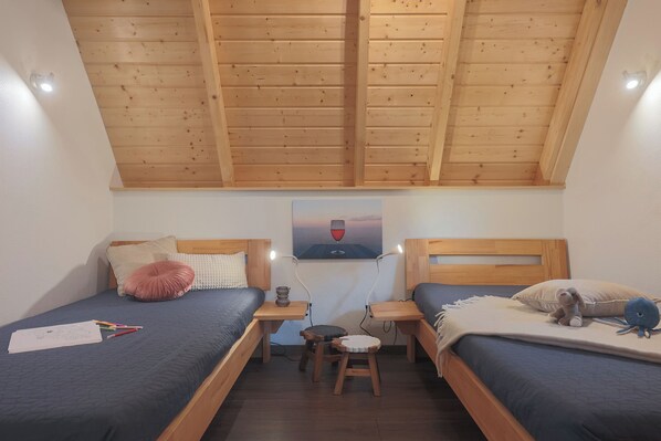 Un dormitorio con dos camas, cabeceros de madera, un taburete pequeño y un cuadro en la pared.