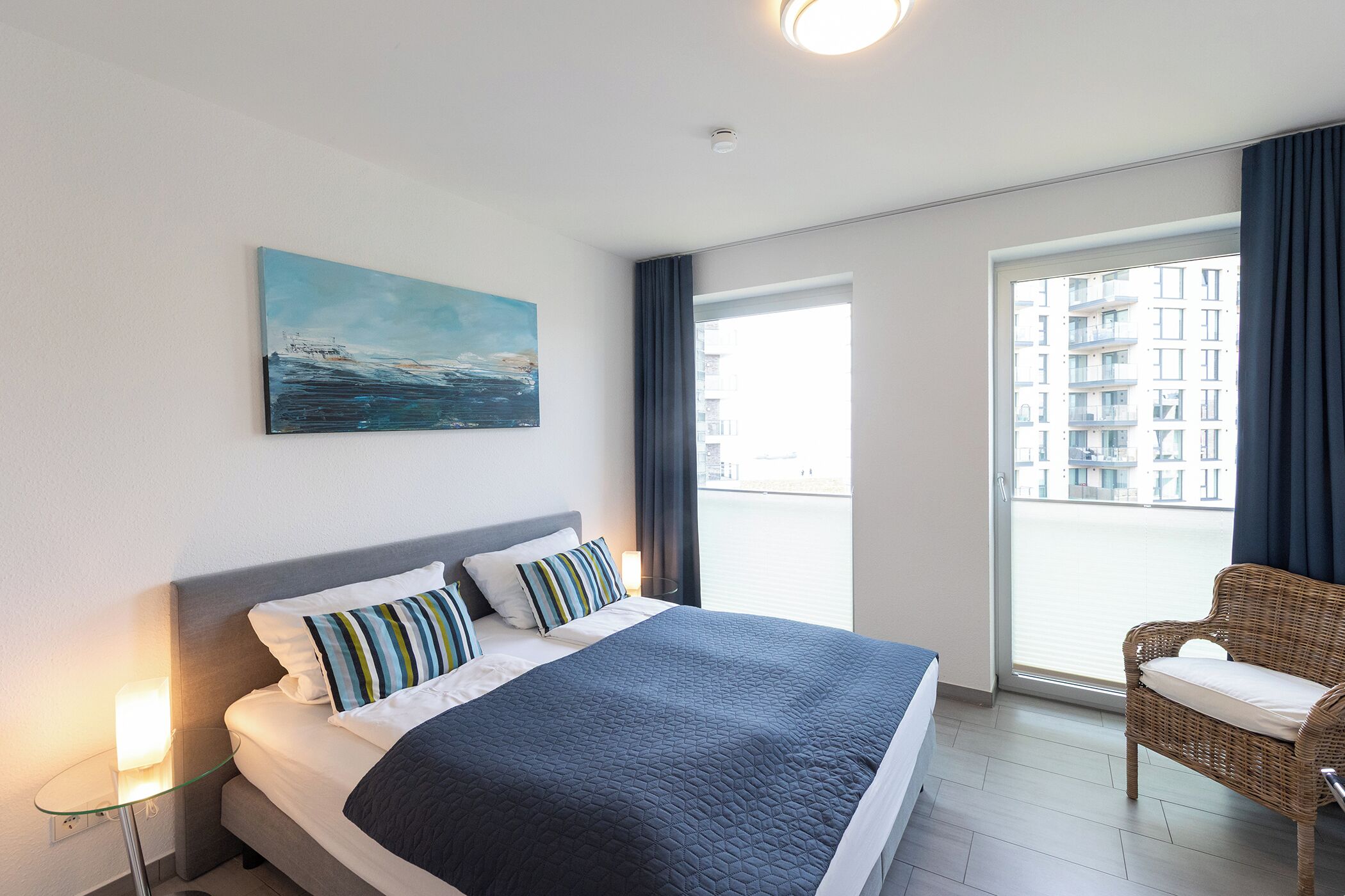 Ein Hotelzimmer mit einem großen Bett, Blick auf die Stadt durch ein Fenster und einem Gemälde an der Wand.
