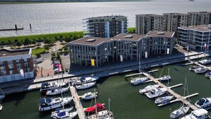 Ein Yachthafen mit mehreren angemeldeten Booten, umgeben von modernen Gebäuden mit Balkonen und großen Fenstern.