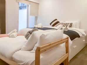 A hotel room with two beds, a wooden headboard, a window with blinds, and a pillow with the text "NOROFF IT". - Modern Beautiful Pool And Sea Apt Qawra (St. Paul's Bay)