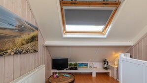 A cozy room with a skylight, a TV, a small table with plants, and a bench. - Studio De Zandhut - Swaalingestraat 78 Zoutelande (Zoutelande)