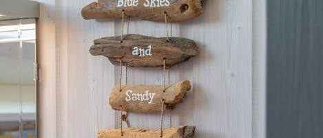 A wooden sign with the words "Blue Skies and Sandy Beaches" hanging on a wall.