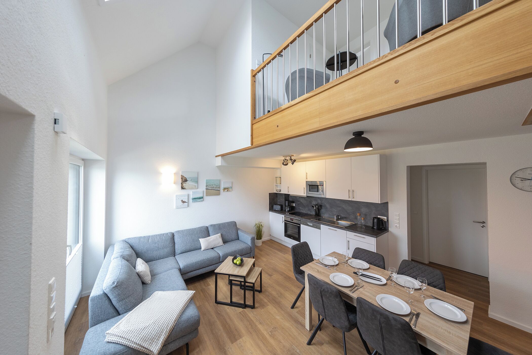 Ein modernes Apartment mit Essbereich, Küche und Wohnzimmer mit Sofa und kleinem Tisch.