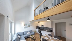 Un appartement moderne comprenant un coin repas, une cuisine et un salon avec un canapé et une petite table.