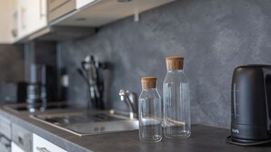 Une cuisine avec deux bouteilles en verre transparent dotées de bouchons en liège, une machine à café noire et un robinet moderne.