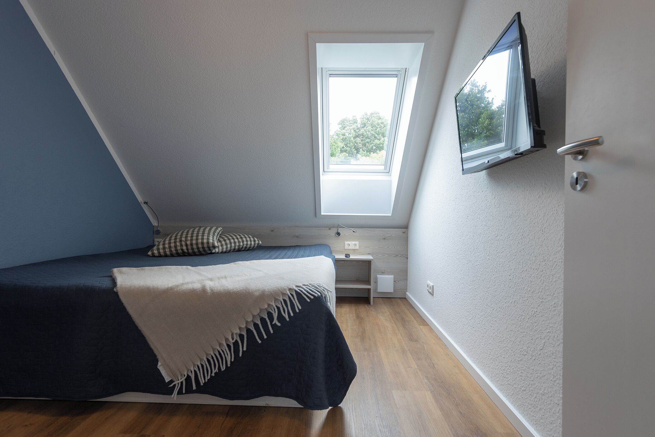 Une chambre à coucher avec un lit, une fenêtre, un téléviseur et une porte.