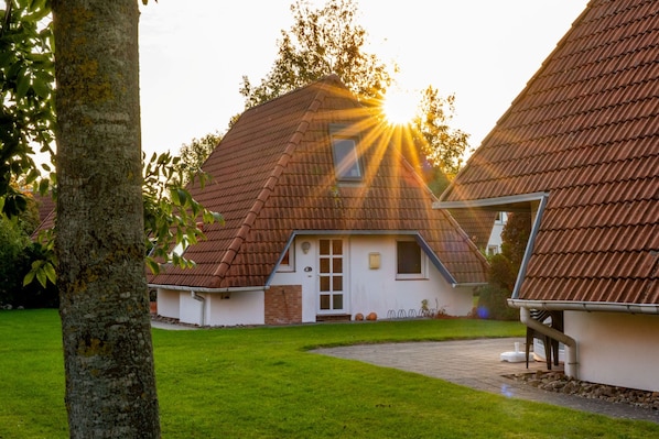 A traditional house with a sloped roof, a front door, and a visible chimney.
