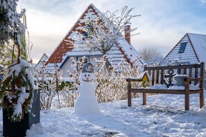 Un muñeco de nieve en un paisaje invernal nevado con casas al fondo.