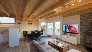 Una sala de estar moderna con un sofá, una mesa de centro, televisor y chimenea.