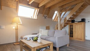 Una sala de estar acogedora con techo de madera, un sofá, una mesa de centro y una lámpara.
