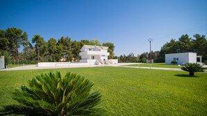 A modern two-story house with a flat roof, surrounded by a well-maintained lawn and trees. - Villa Cristal Pool and Padel (Galatina)