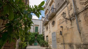 A narrow cobblestone street flanked by historic buildings with balconies and a green door. - Villa Cristal Pool and Padel (Galatina)
