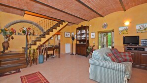 A spacious living room with a staircase, a television, and a sofa.