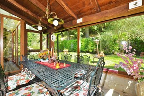A wooden interior with a table and chairs, large windows, and a garden view.