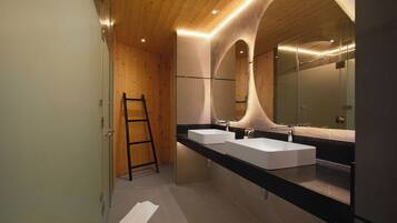 Un baño moderno con techo de madera, dos lavamanos y un espejo grande.