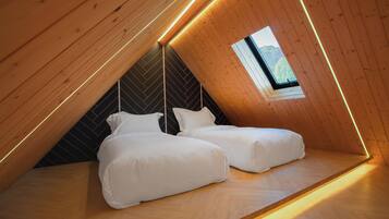 Un dormitorio acogedor en el ático, con dos camas, paredes de madera y un tragaluz.