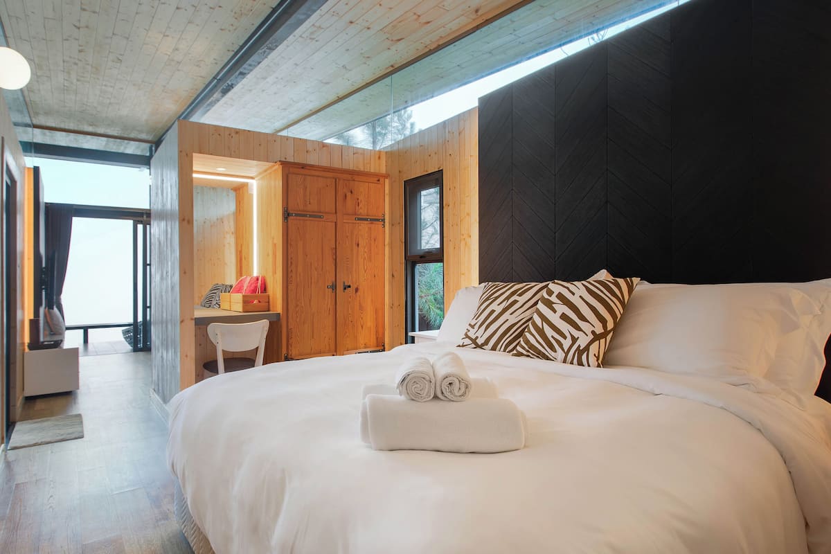 Ein Schlafzimmer mit einem großen Bett, einem Holzschrank und einem kleinen Schreibtisch mit Stuhl.