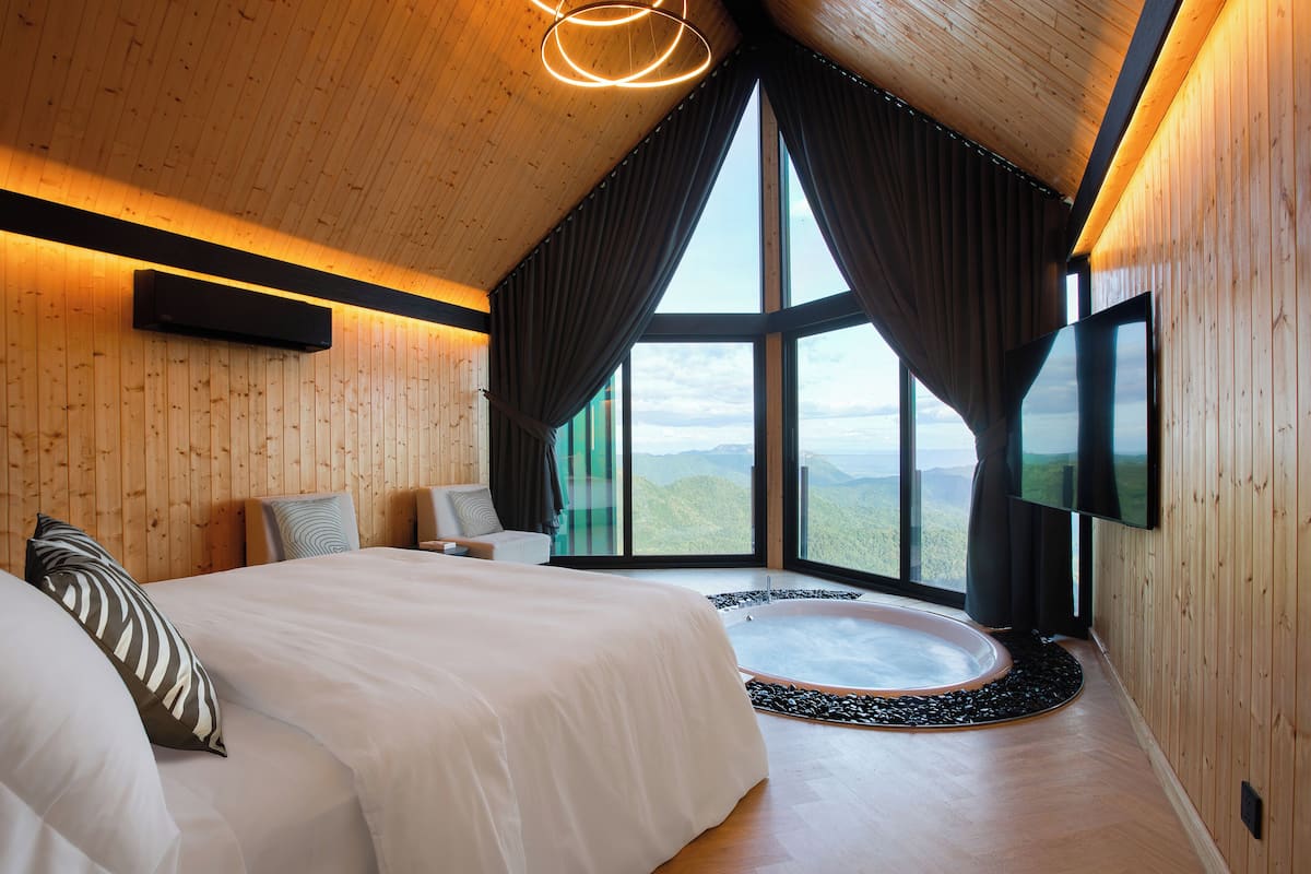 Ein Schlafzimmer mit einem großen Bett, Bergblick und einer Hot Tub.