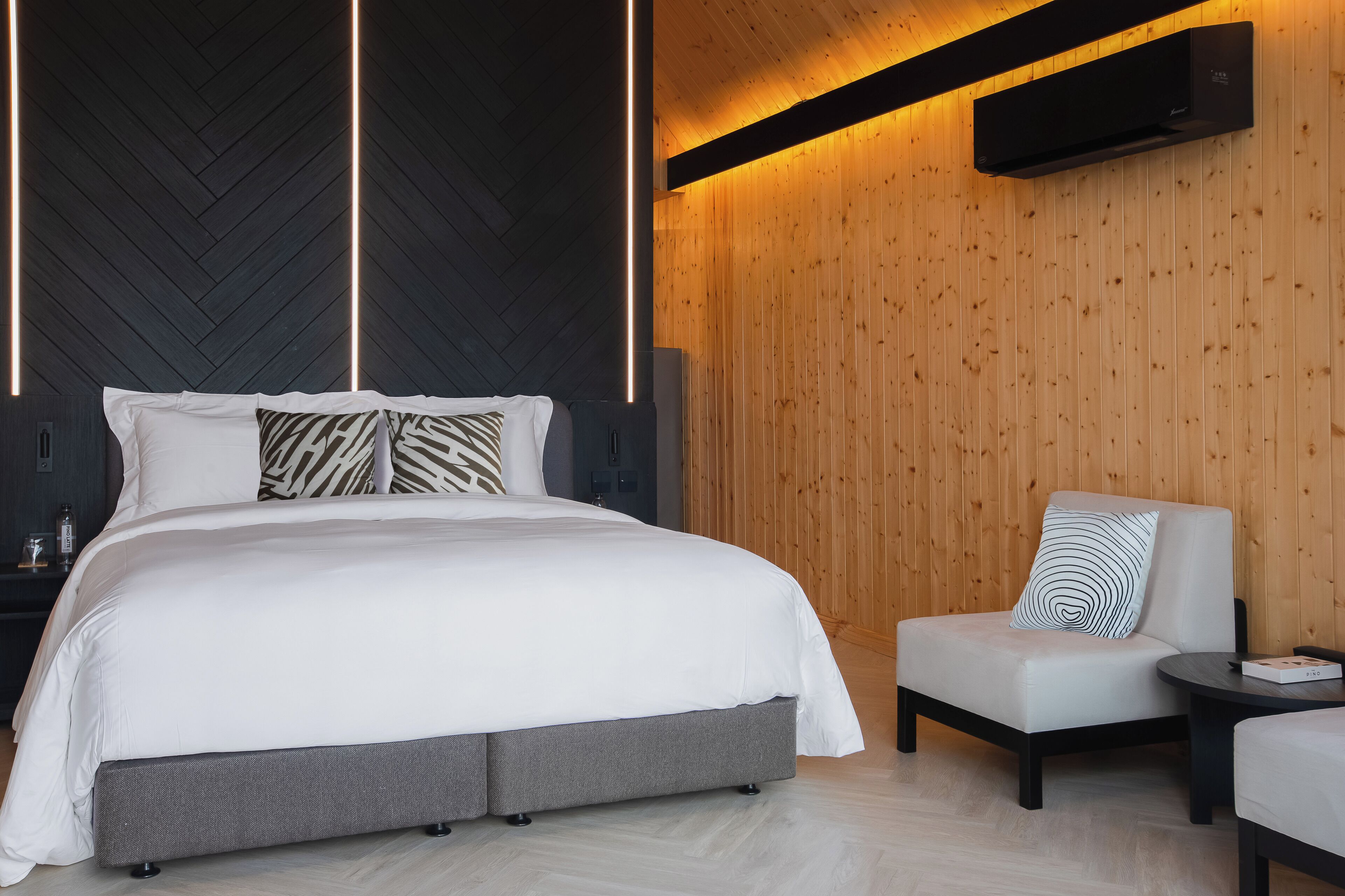 A modern bedroom with a large bed, a chair, and a small table.