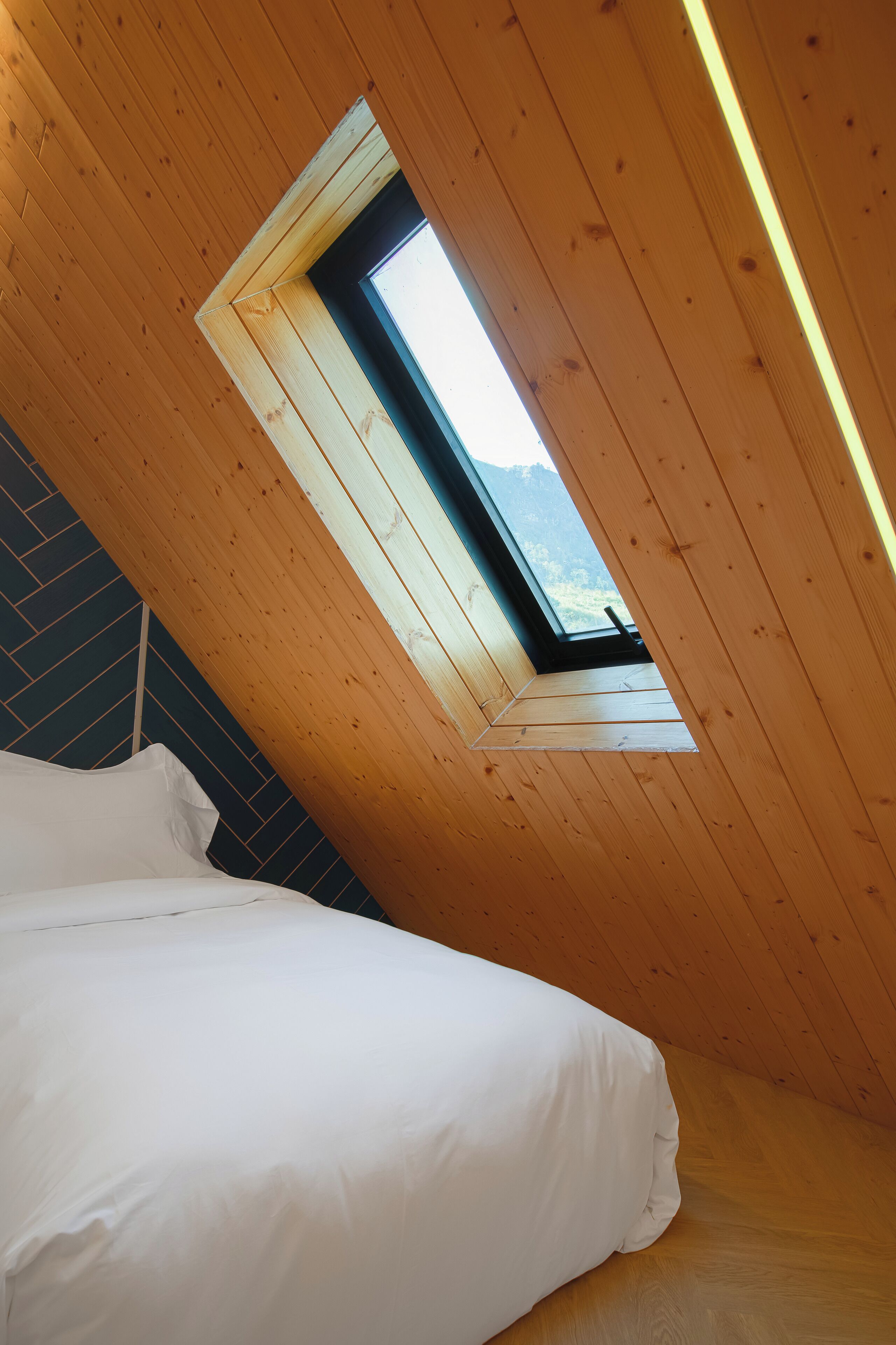 Une chambre avec un plafond en pente et un puits de lumière.