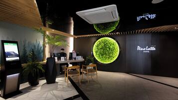 A hotel reception area with a digital display, reception desk, and a large circular green wall.