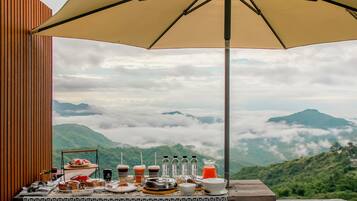 A table with breakfast items and a view of mountains and clouds.