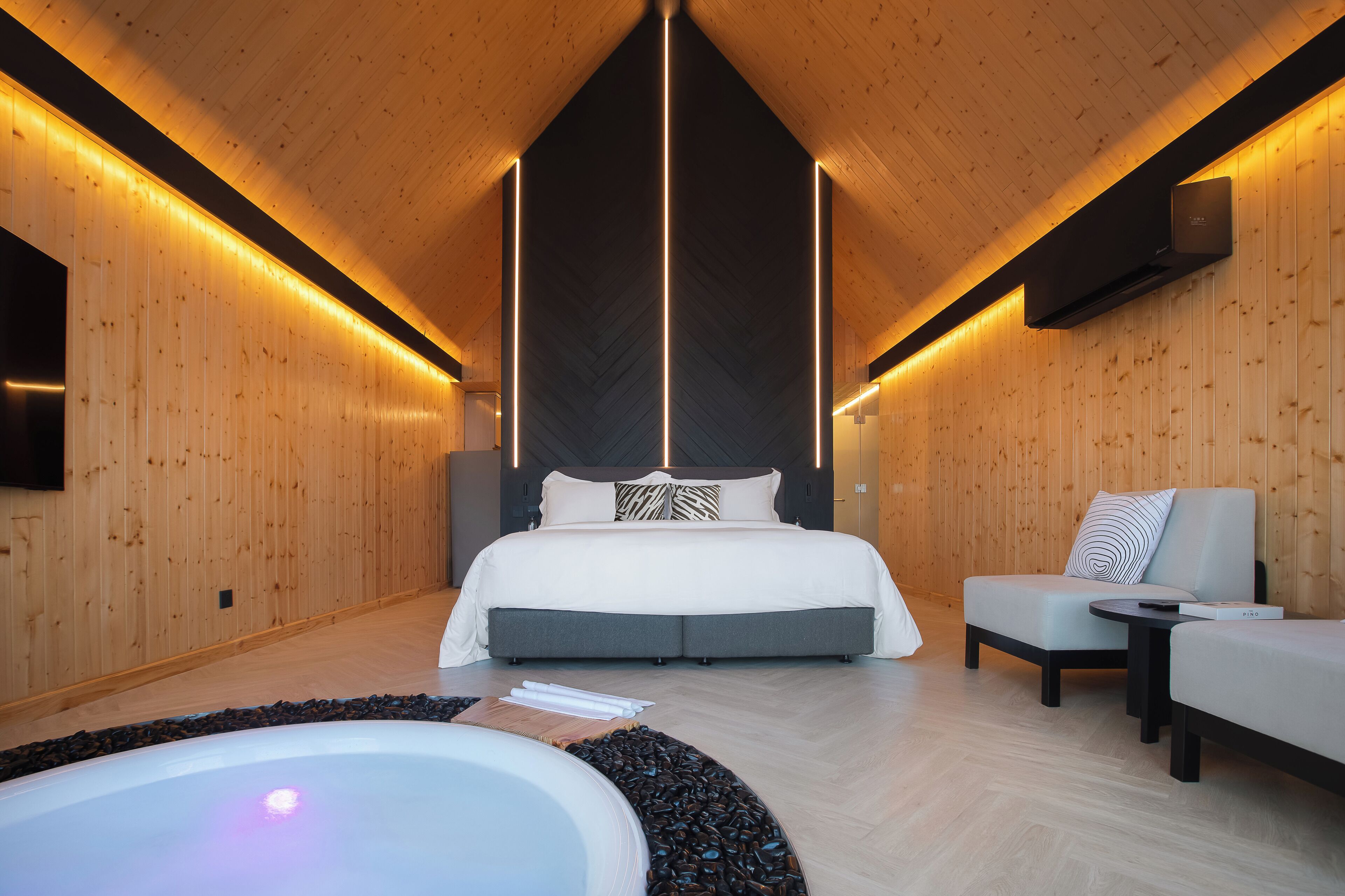 Une chambre moderne avec un grand lit, un coin salon et une baignoire.
