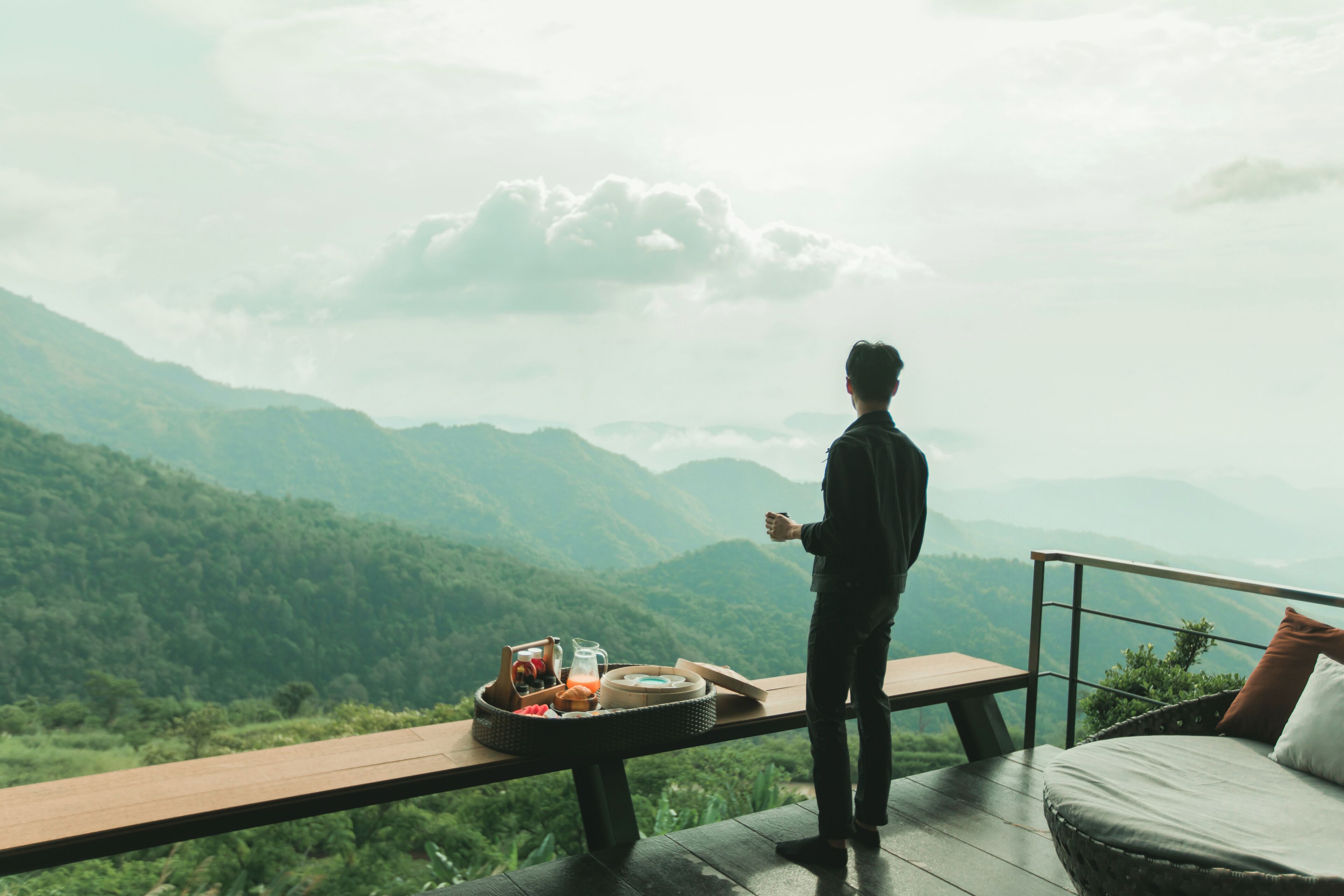 A person standing on a balcony overlooking a mountainous landscape.