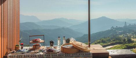 Une table dressée à l’extérieur, avec une vue sur les montagnes et un temple en arrière-plan.