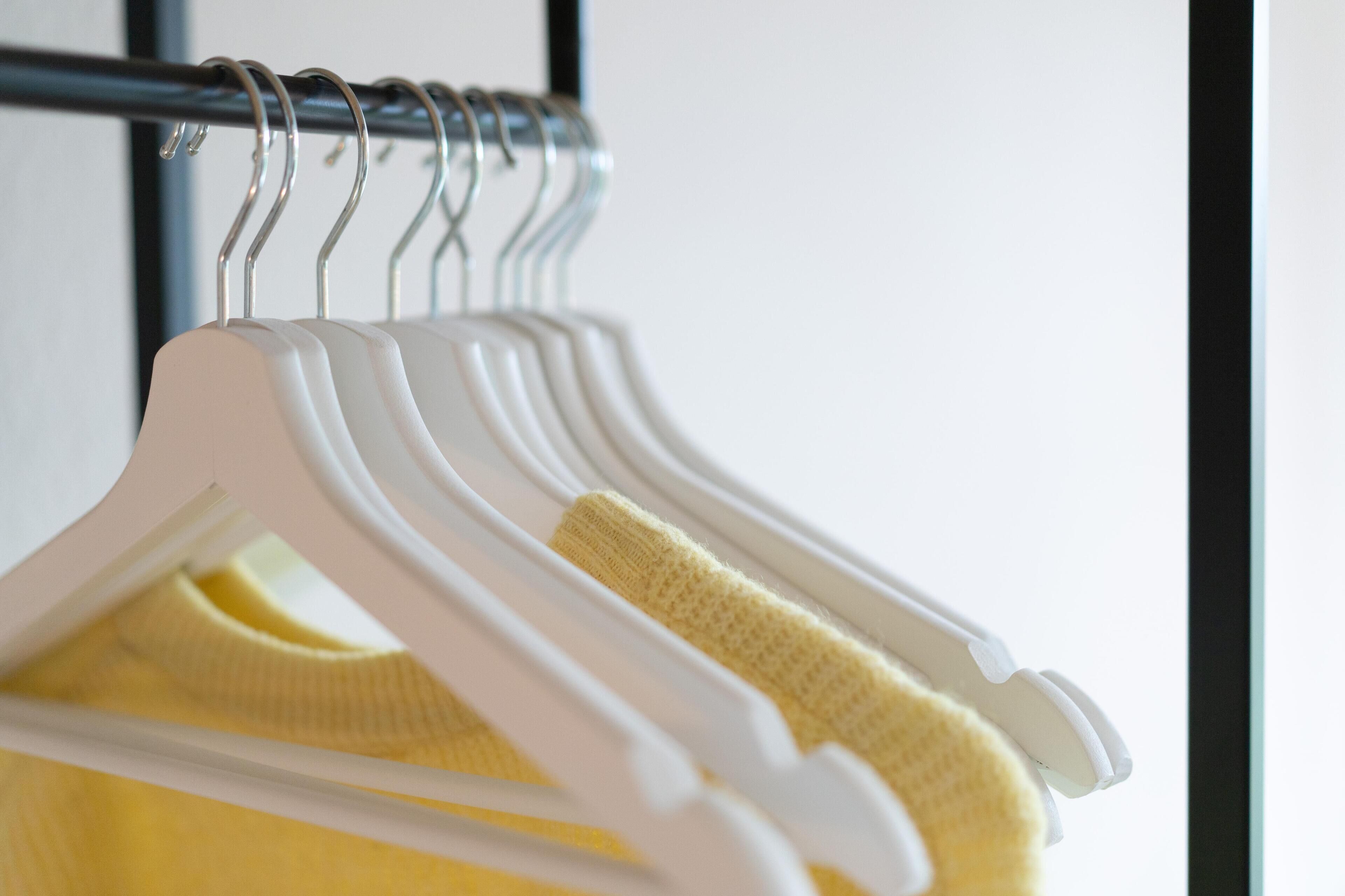 A rack of white hangers with a yellow garment.