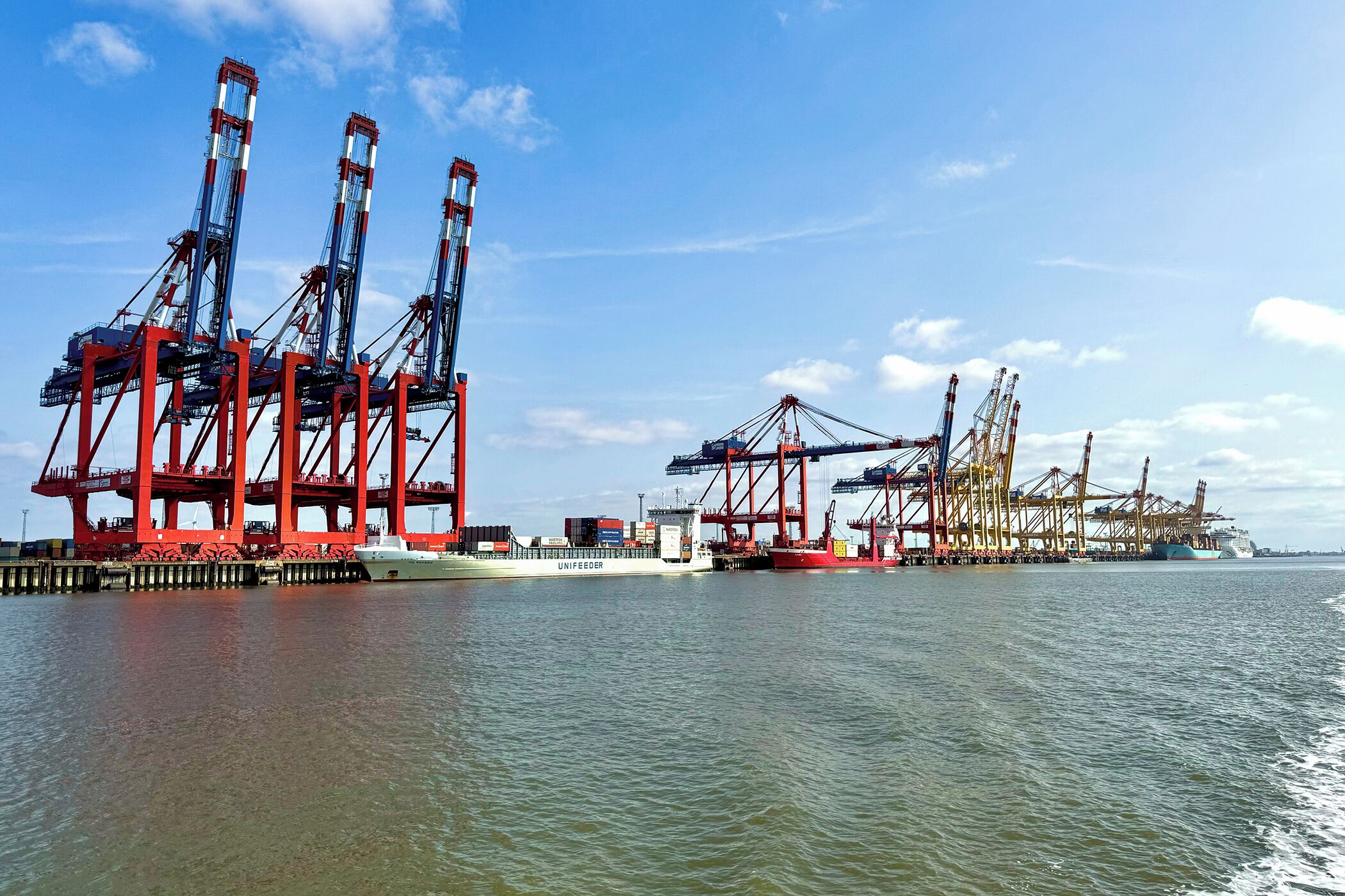 A cargo ship docked at a port with multiple cranes and containers.