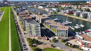 A marina with boats, a river, and buildings with balconies. - Vacation apartment Moni's Haven. Dream view and loggia. (Bremerhaven)