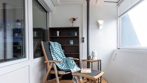 A cozy balcony with a wooden chair, a small table, and a bookshelf. - Vacation apartment Moni's Haven. Dream view and loggia. (Bremerhaven)