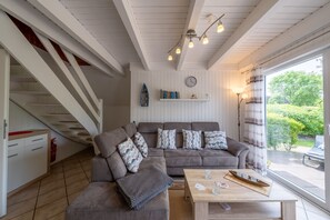 A cozy living room with a sofa, a coffee table, and a staircase. - Vacation home Rotersand 2 - charming and in the middle of the action. (Wurster Nordseeküste)