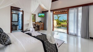 A hotel room with a bed, a desk, and a TV. There is a balcony with a view of the outdoors.