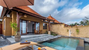 A poolside area with lounge chairs, a stone wall, and a tiled roof.