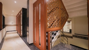A hotel corridor with a marble floor, wooden doors, and a staircase with metal railings. - Park Avenue Hotel (Bengaluru)