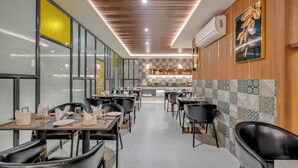 A restaurant with a long counter, black chairs, and a tiled backsplash. - Park Avenue Hotel (Bengaluru)