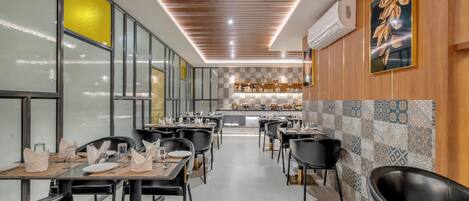 Un restaurante con una barra larga, sillas negras y un salpicadero de azulejos.
