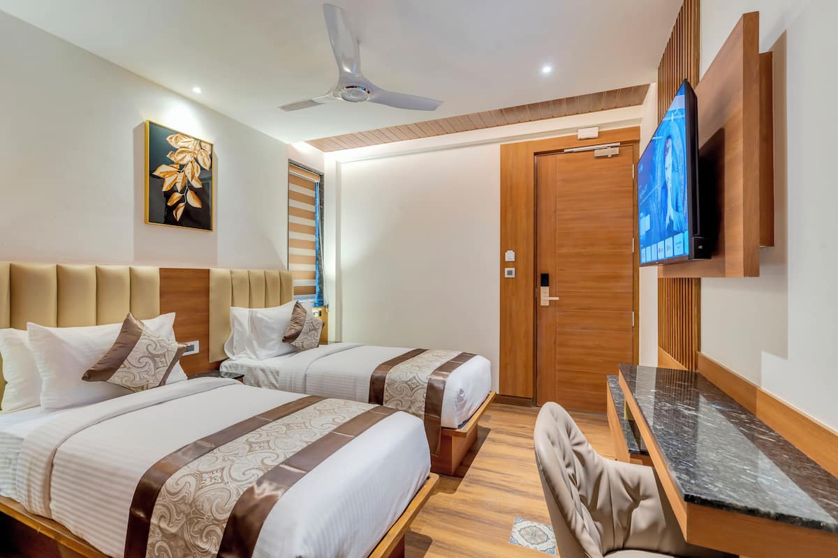 Une chambre d’hôtel avec deux lits, un bureau, une télévision et un ventilateur de plafond.