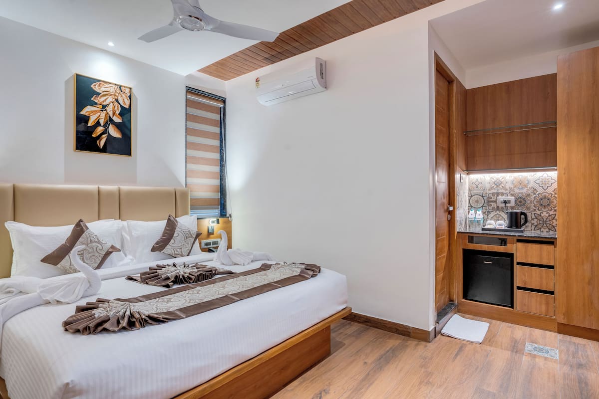 Une chambre d’hôtel comprenant un lit, un ventilateur de plafond, un climatiseur, un petit coin cuisine et un élément décoratif mural.