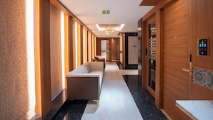 A hotel hallway with a modern design, featuring a sofa, a reception desk, and a door with a number plate. - Park Avenue Hotel (Bengaluru)