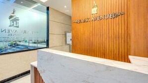 A reception desk with a marble top and a wooden panel backdrop displaying the name "Park Avenue." - Park Avenue Hotel (Bengaluru)