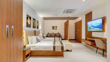 A modern bedroom with a large bed, a TV, and a desk.