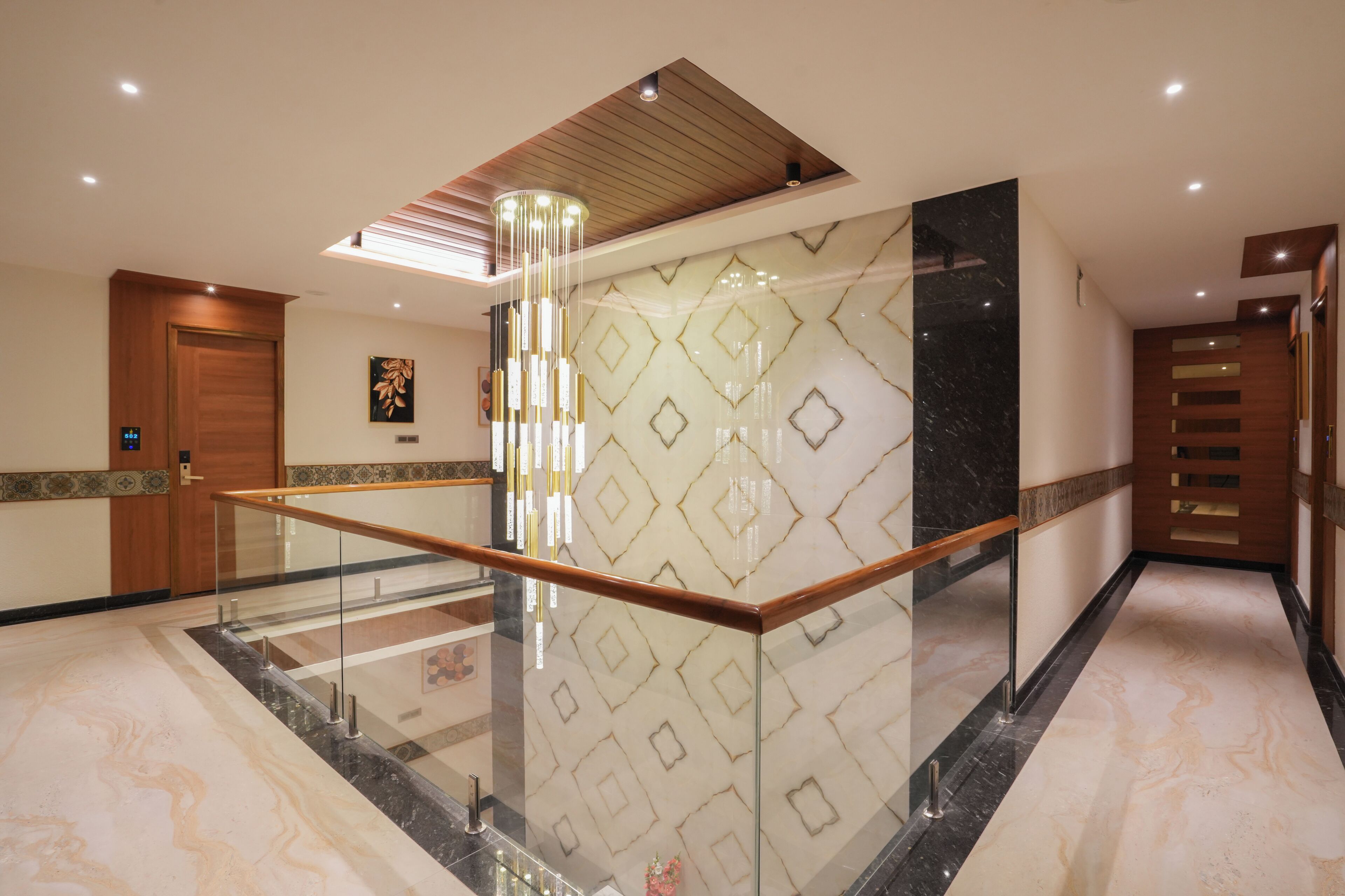 A modern interior with a glass railing, marble flooring, and a geometric patterned wall.