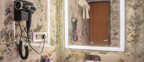 Un baño con lavamanos de mármol, secador de pelo y espejo con iluminación.