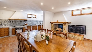 A spacious kitchen with a dining area, featuring a stone fireplace, tiled backsplash, and wooden cabinetry. - Villa Vittoriano - Surrounded By Nature (Camaiore)